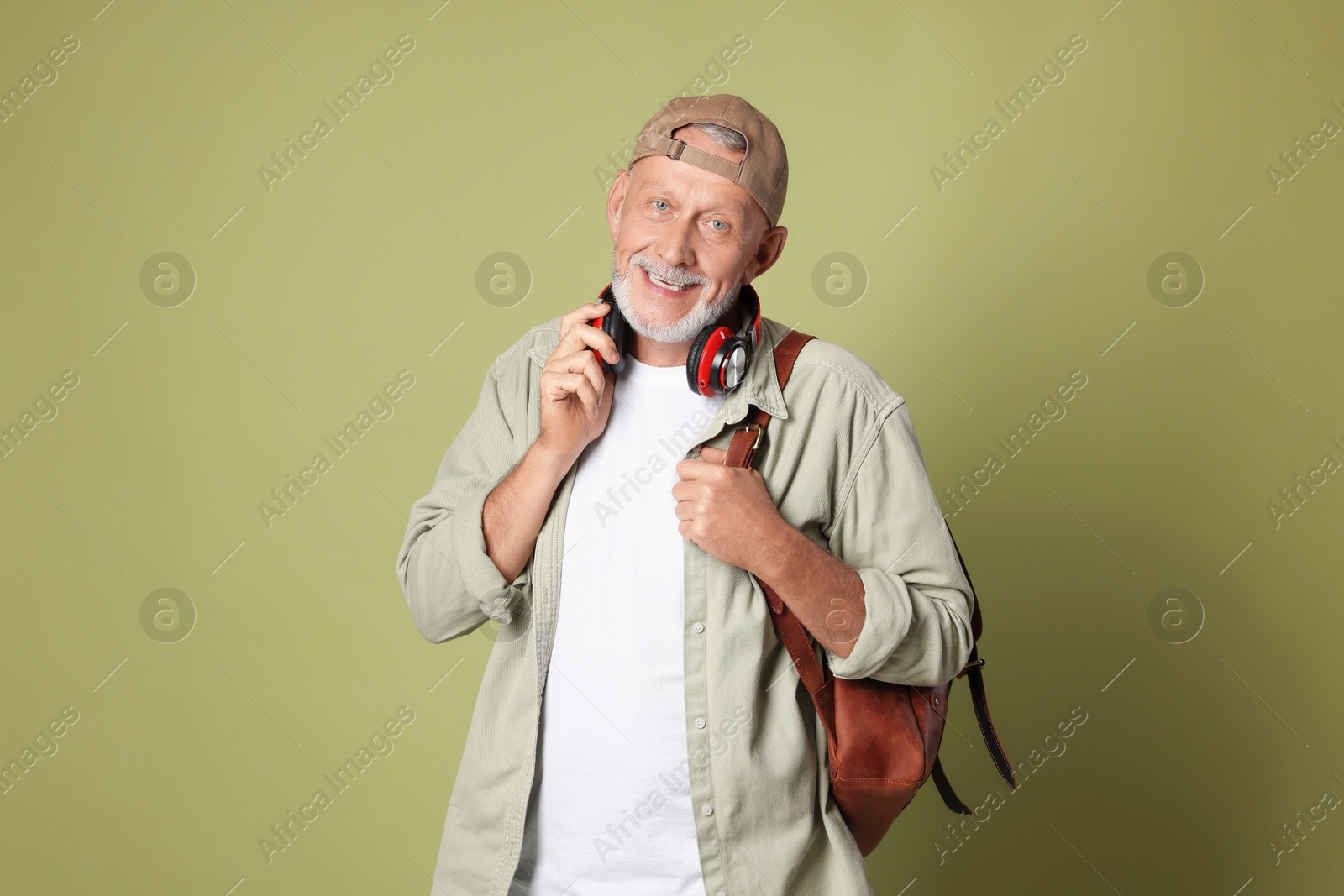 Photo of Portrait of happy senior man with headphones on green background