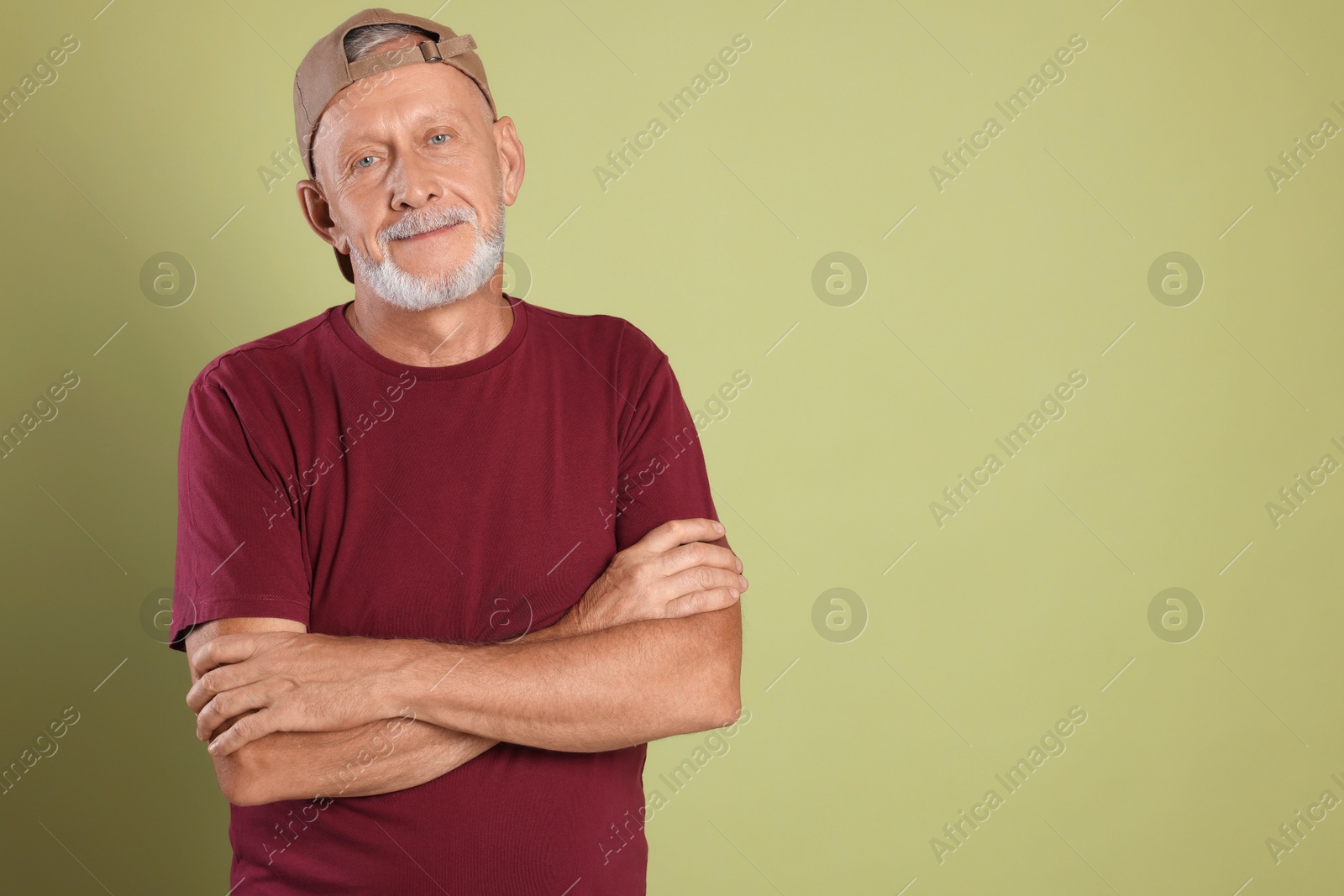 Photo of Portrait of handsome senior man with crossed arms on green background. Space for text