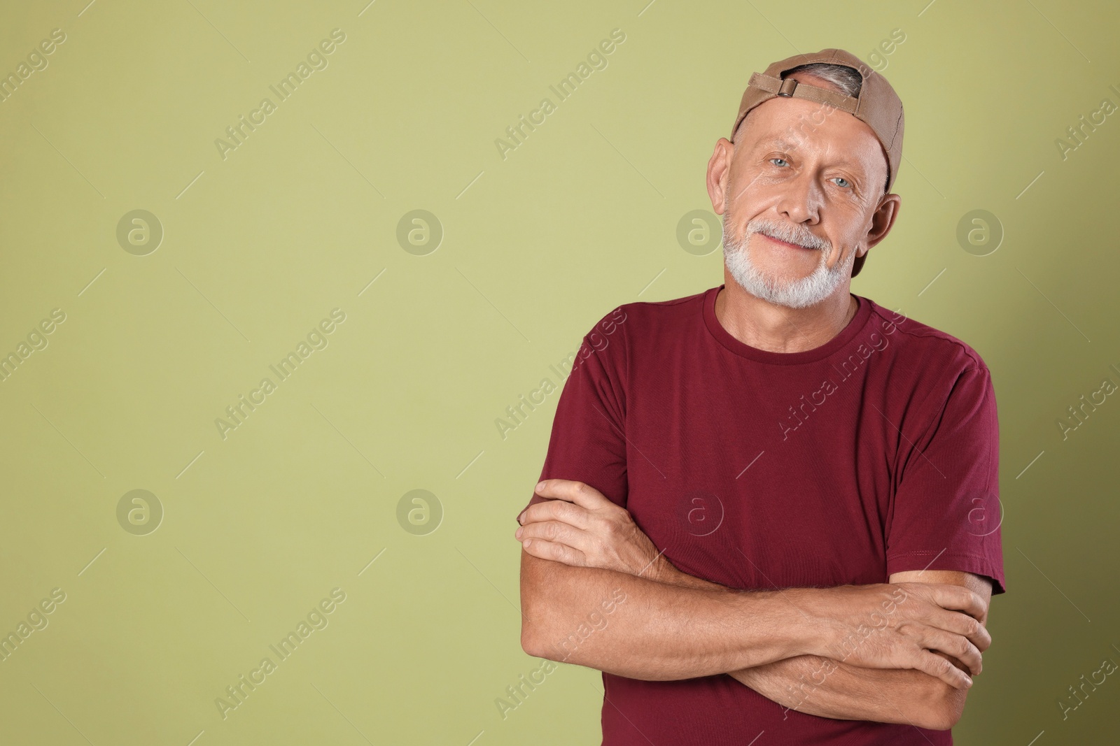 Photo of Portrait of handsome senior man with crossed arms on green background. Space for text