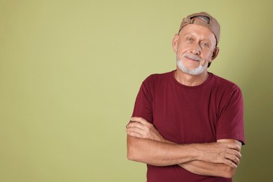 Portrait of handsome senior man with crossed arms on green background. Space for text