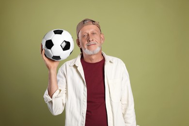 Portrait of handsome senior man with soccer ball on green background