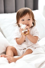 Photo of Cute little baby with rattle on bed at home