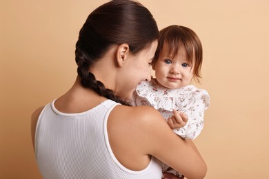 Photo of Beautiful young mother and her cute little baby on beige background