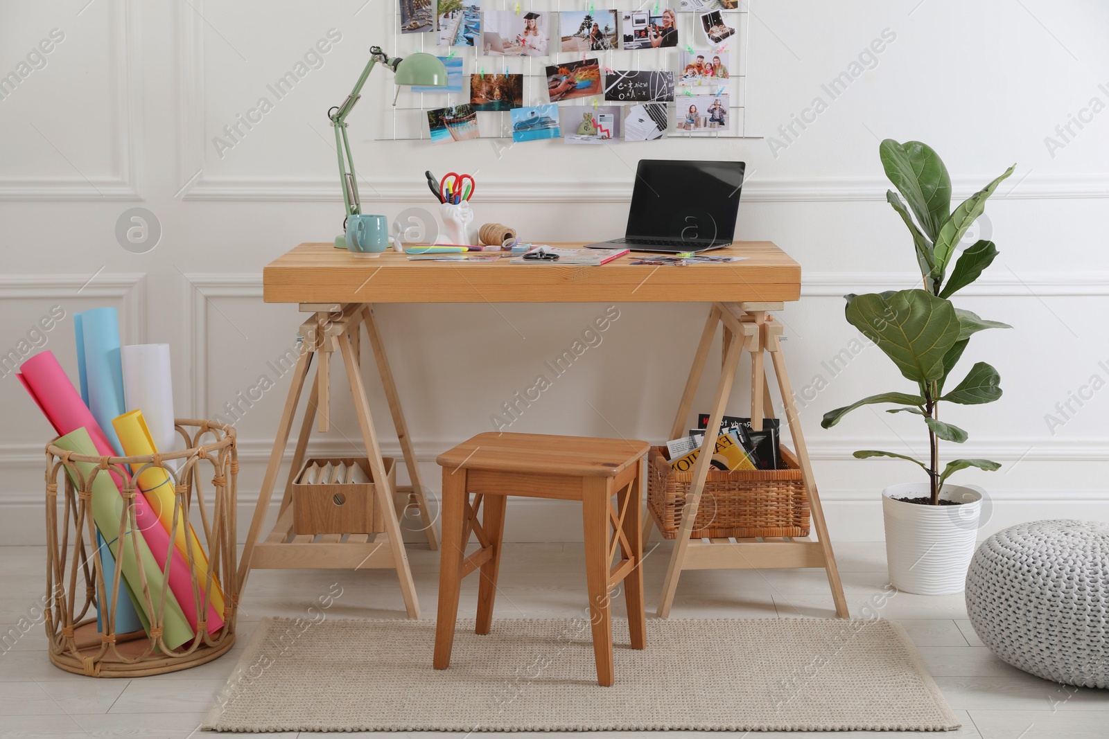 Photo of Stylish room interior with stool, table, houseplant and vision board