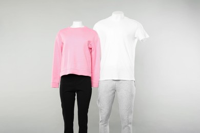 Female and male mannequins with stylish outfits on light background