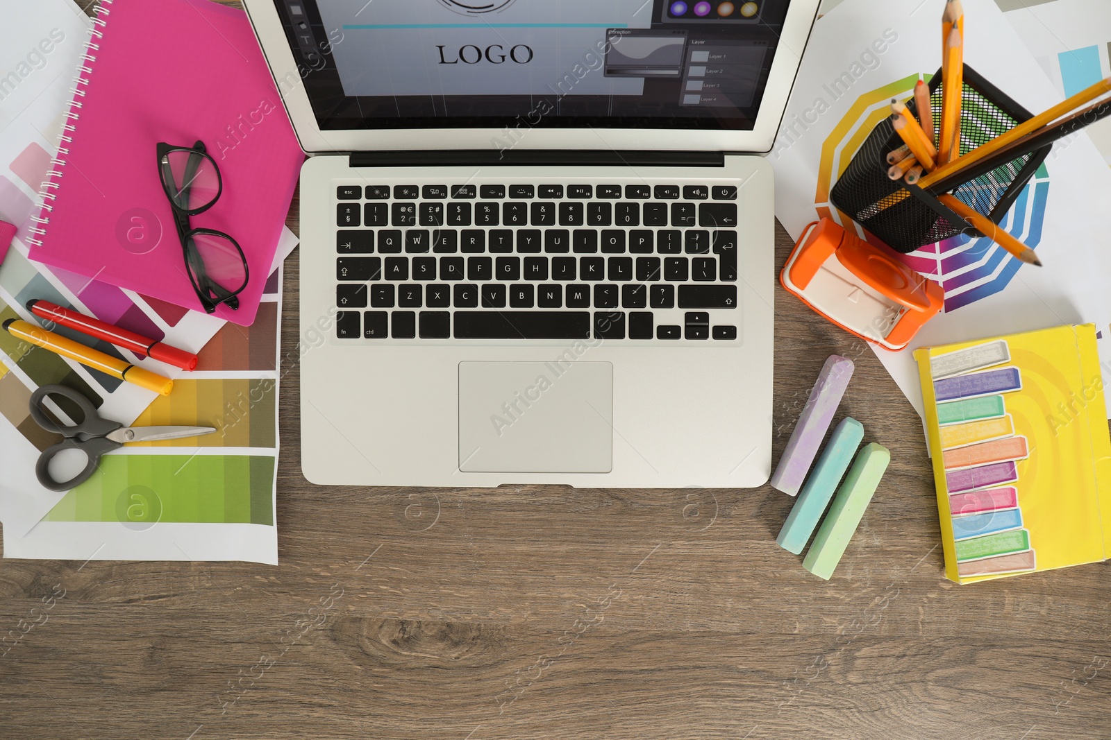 Photo of Fashion designer`s workplace with laptop, color palette and different stationery on wooden table, flat lay