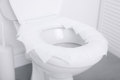 Photo of Toilet seat with paper tissues in bathroom