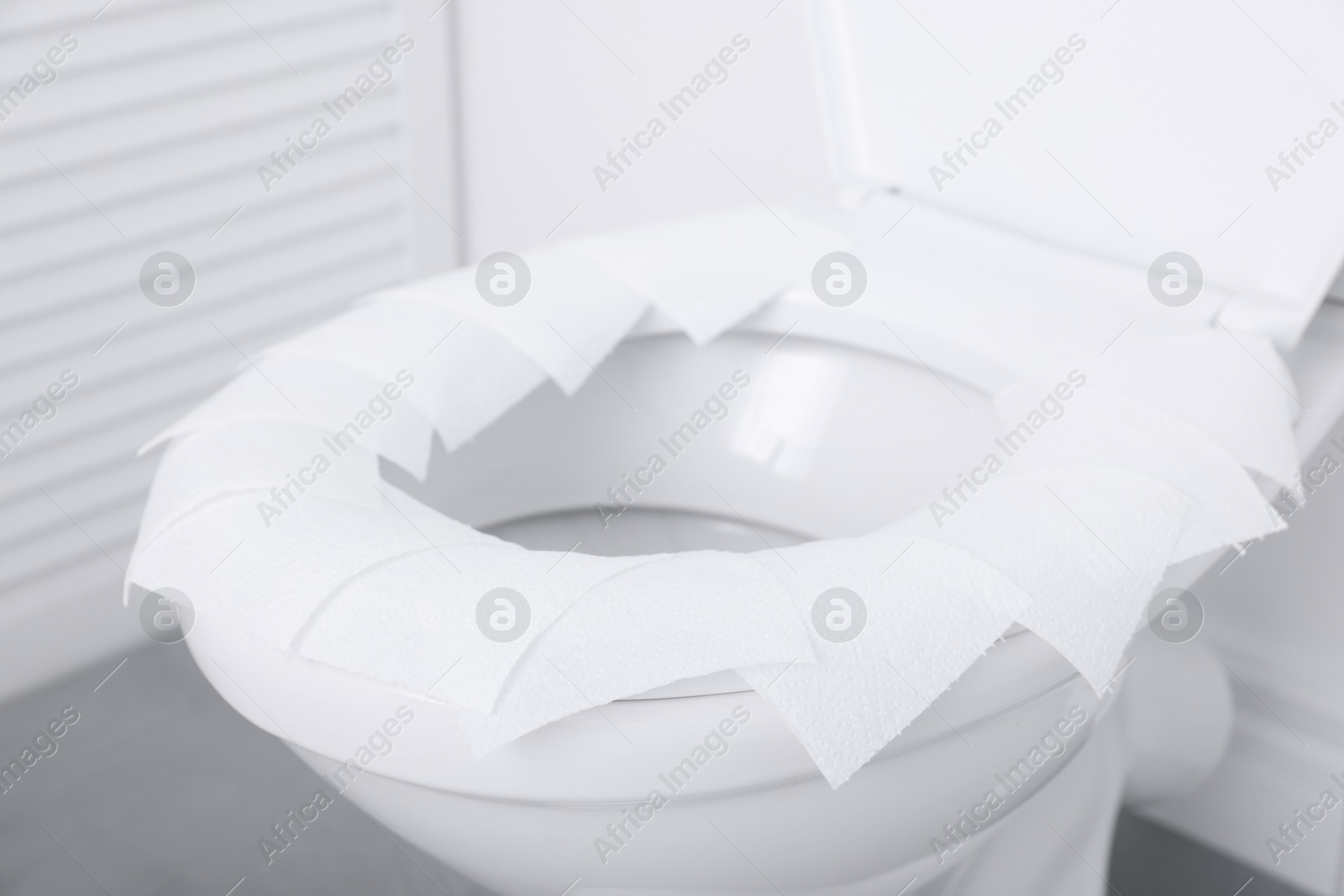 Photo of Toilet seat with paper tissues in bathroom