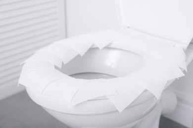 Photo of Toilet seat with paper tissues in bathroom