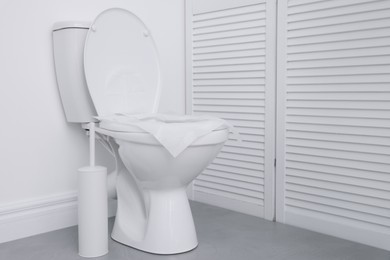 Photo of Toilet seat with paper tissues in bathroom, space for text