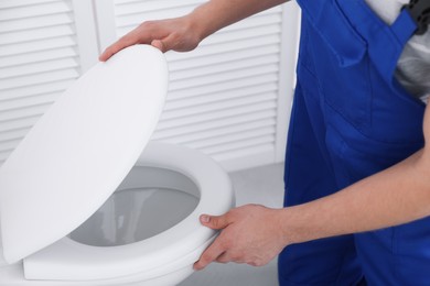 Photo of Man fixing toilet seat in bathroom, closeup