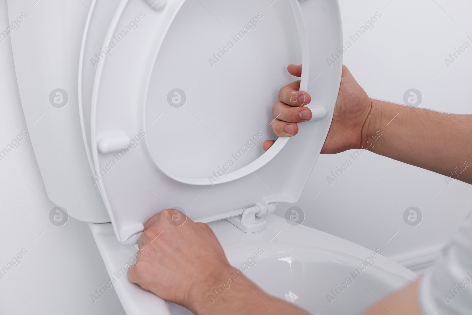 Photo of Man fixing toilet seat in bathroom, closeup