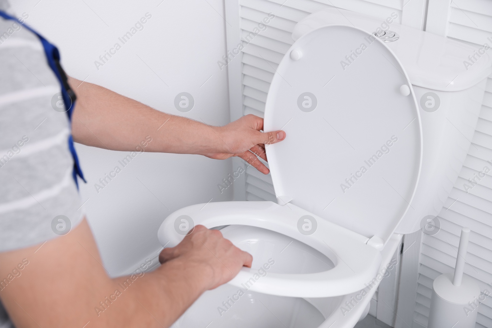 Photo of Man fixing toilet seat in bathroom, closeup