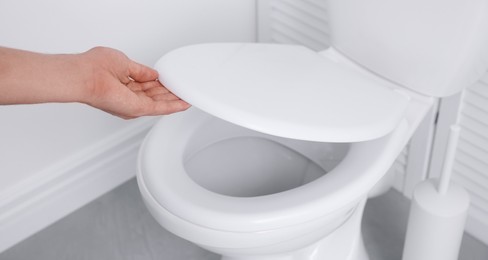 Photo of Man closing toilet seat in bathroom, closeup