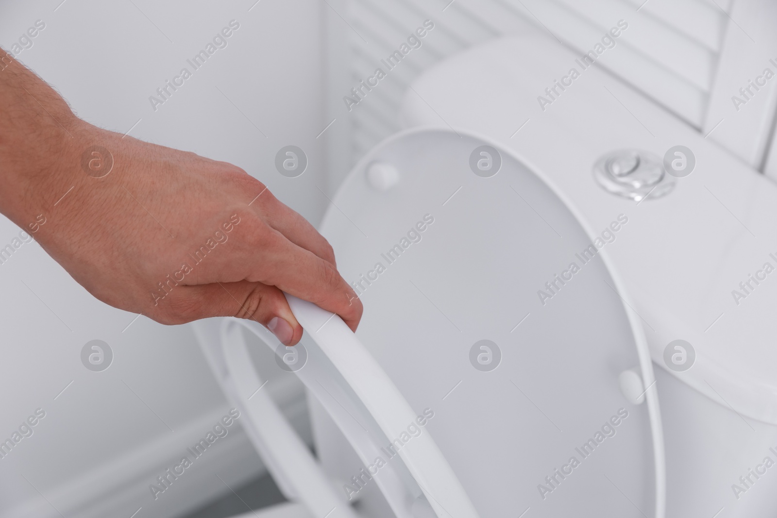 Photo of Man closing toilet seat in bathroom, closeup