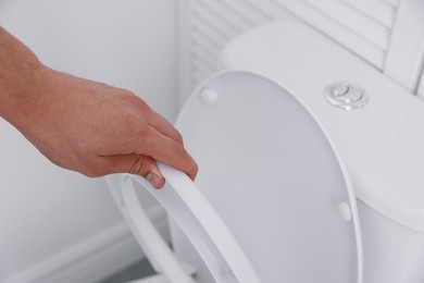 Photo of Man closing toilet seat in bathroom, closeup