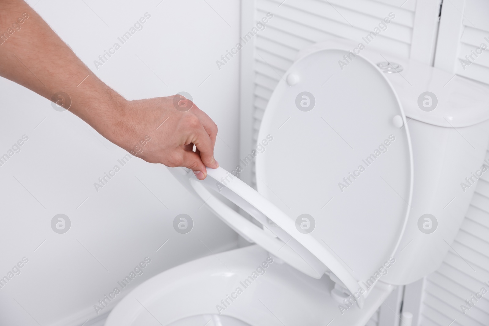 Photo of Man closing toilet seat in bathroom, closeup