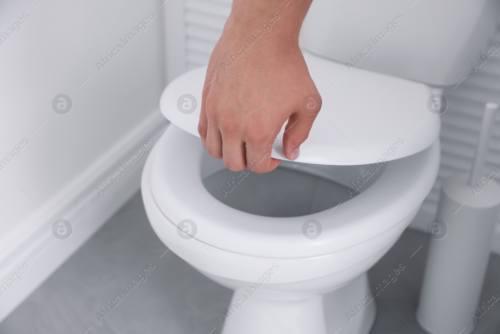 Photo of Man closing toilet seat in bathroom, closeup