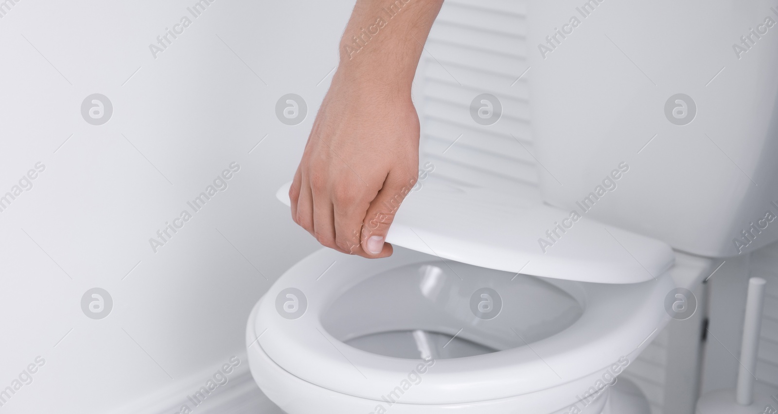 Photo of Man closing toilet seat in bathroom, closeup