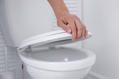 Man closing toilet seat in bathroom, closeup