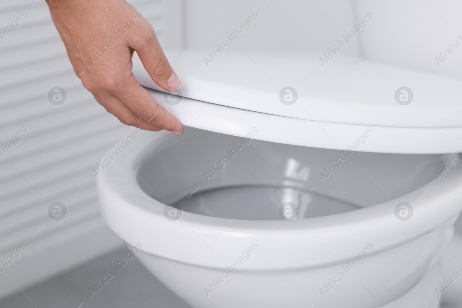 Photo of Woman closing toilet seat in bathroom, closeup