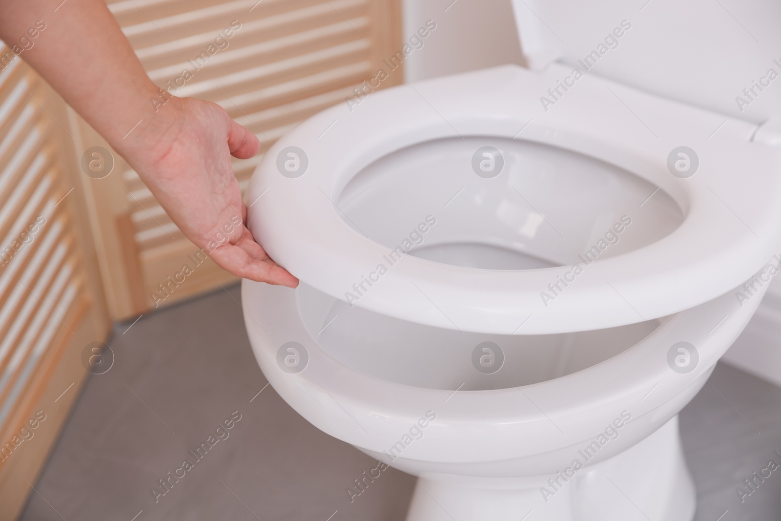 Photo of Woman closing toilet seat in bathroom, closeup