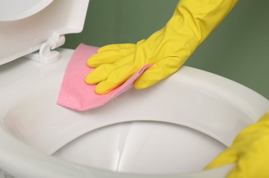 Photo of Woman cleaning toilet bowl in restroom, closeup