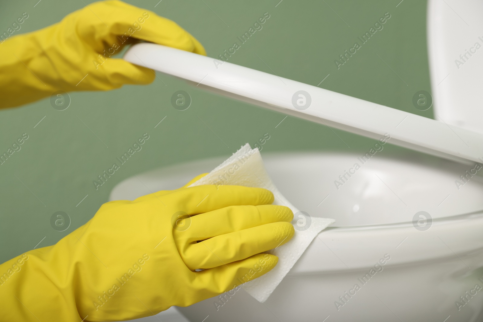 Photo of Woman cleaning toilet bowl in restroom, closeup