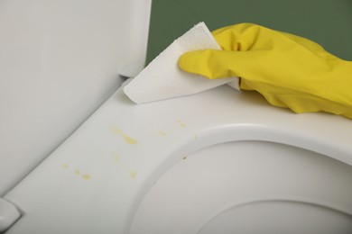 Photo of Woman wiping urine drops from toilet seat in restroom, closeup