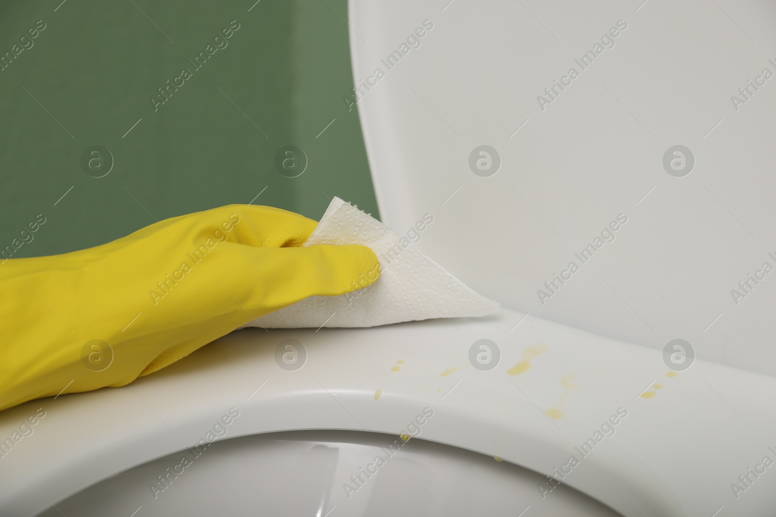 Photo of Woman wiping urine drops from toilet seat in restroom, closeup