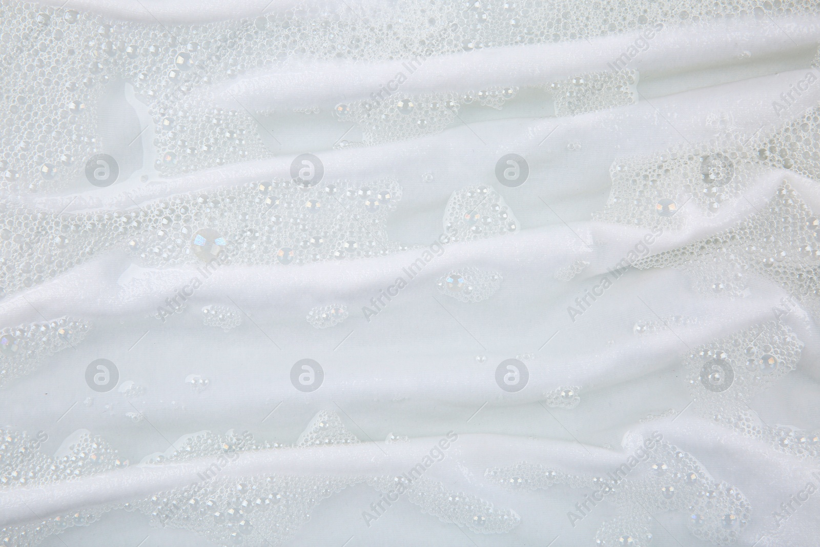 Photo of Washing laundry in water with foam, top view