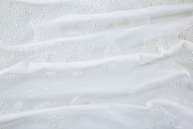 Photo of Washing laundry in water with foam, top view