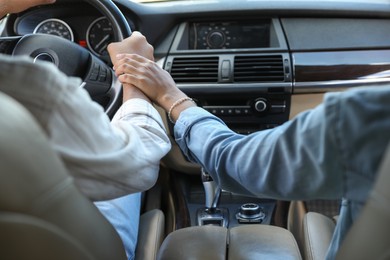 Lovely couple holding hands together while traveling by car, closeup