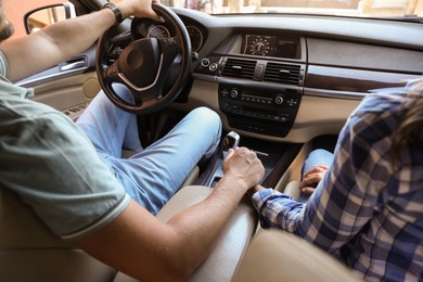 Lovely couple holding hands together while traveling by car, closeup