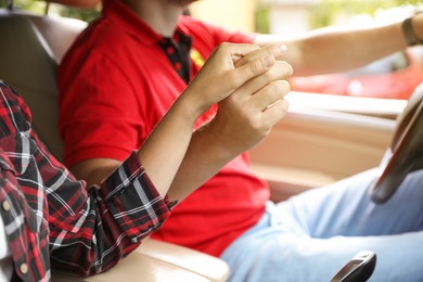 Photo of Lovely couple holding hands together while traveling by car, closeup