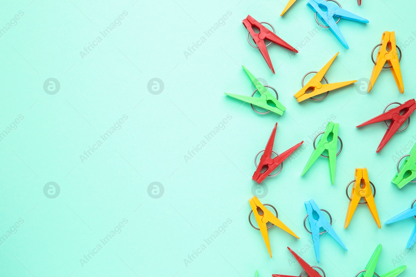 Photo of Many colorful clothespins on turquoise background, flat lay. Space for text