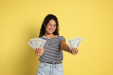 Photo of Happy woman with dollar banknotes on yellow background