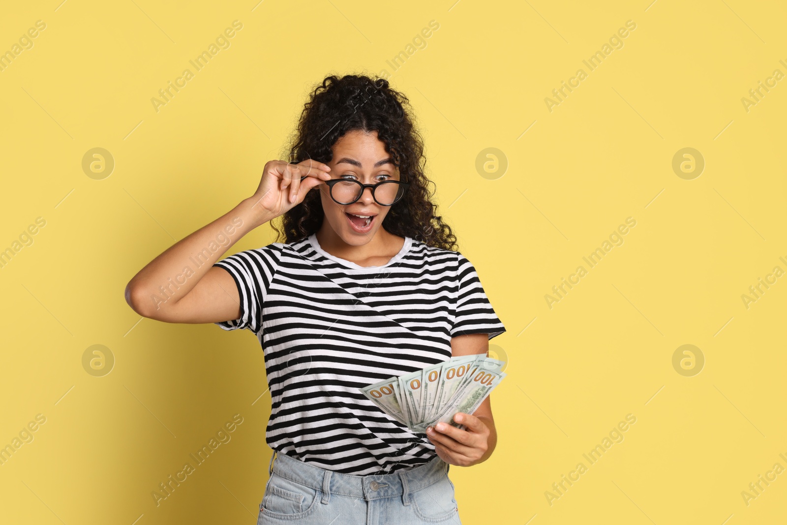 Photo of Shocked woman with dollar banknotes on yellow background