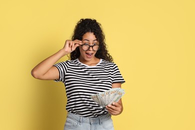 Photo of Shocked woman with dollar banknotes on yellow background