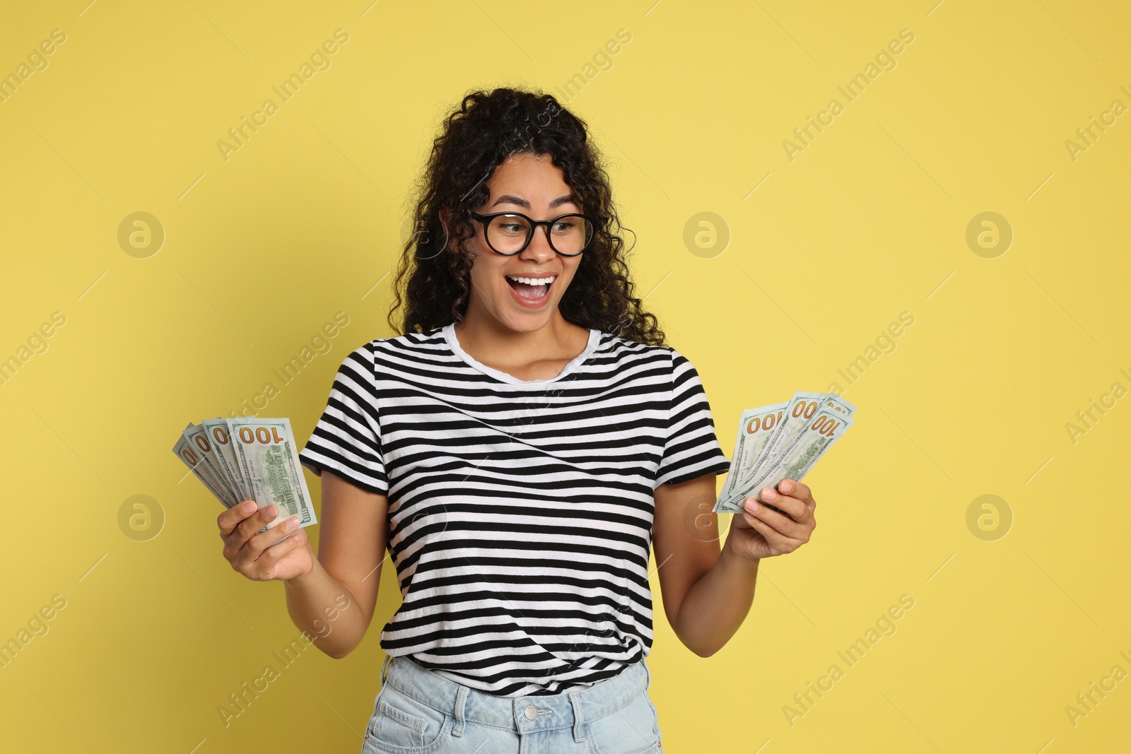 Photo of Happy woman with dollar banknotes on yellow background