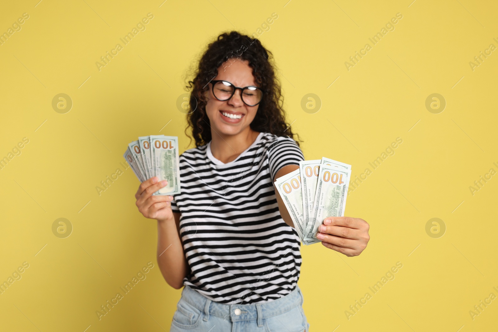 Photo of Happy woman with dollar banknotes on yellow background