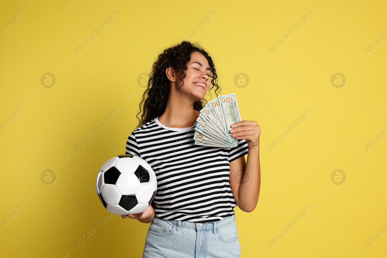 Photo of Happy woman with money and soccer ball on yellow background