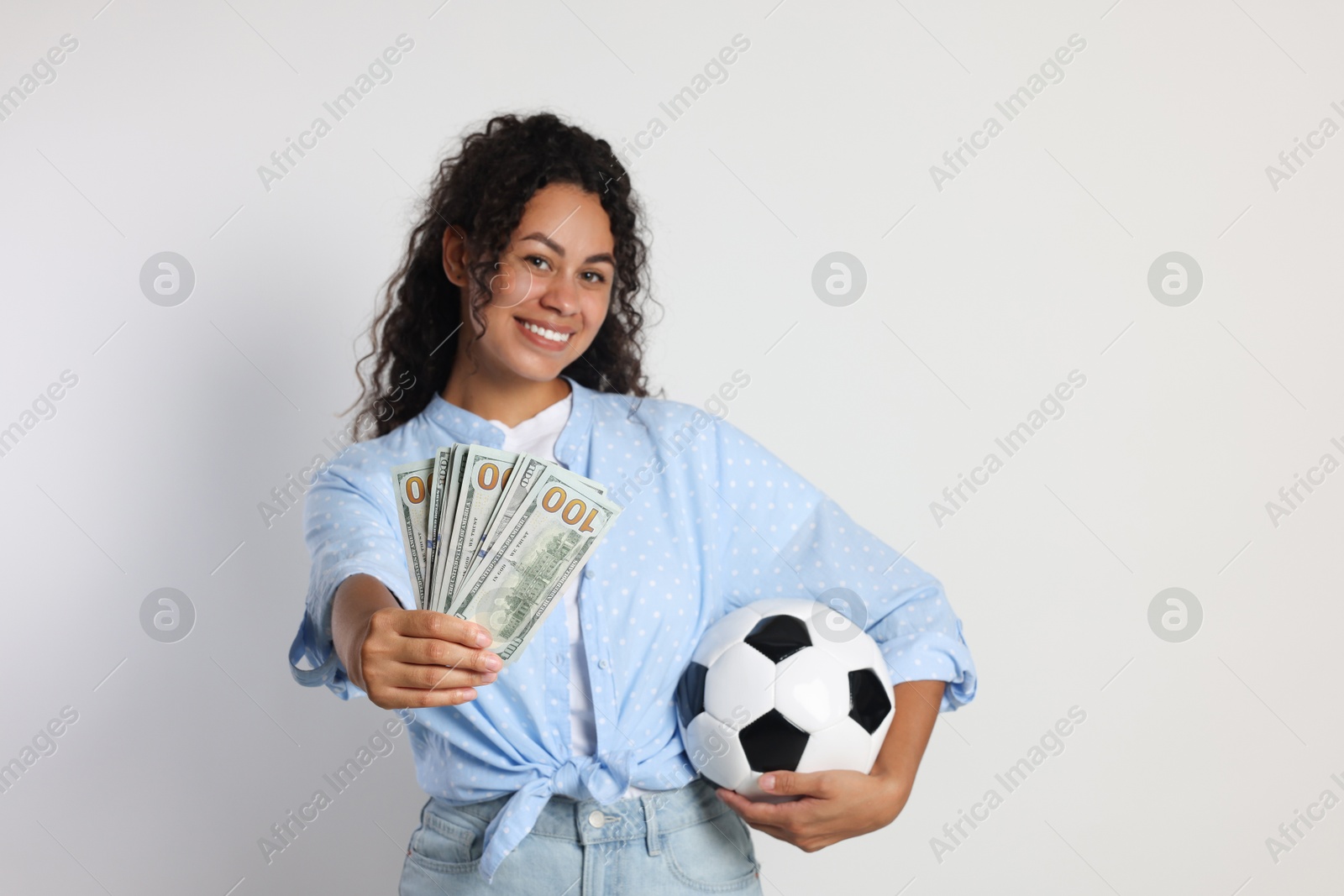 Photo of Happy woman with money and soccer ball on light grey background