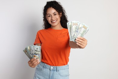 Photo of Happy woman with dollar banknotes on light grey background