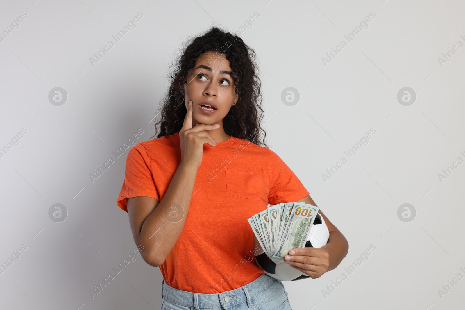 Photo of Woman with money and soccer ball on light grey background