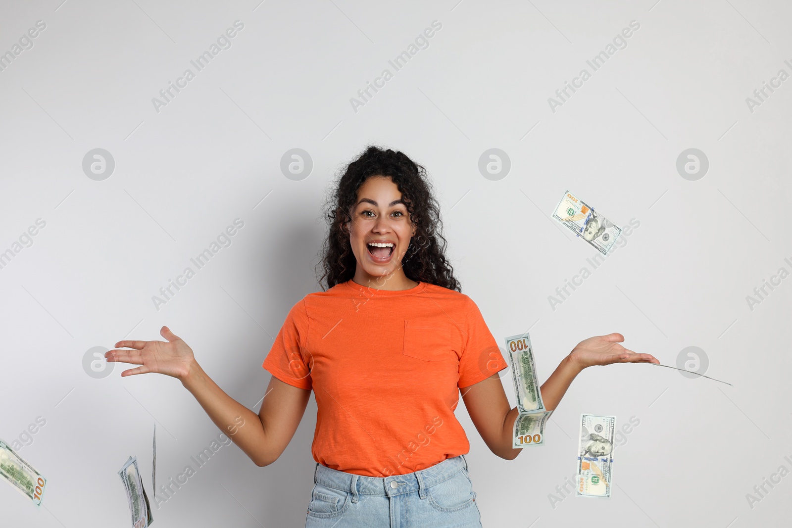 Photo of Happy woman under money shower on light grey background