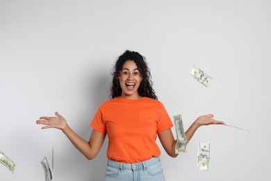 Happy woman under money shower on light grey background