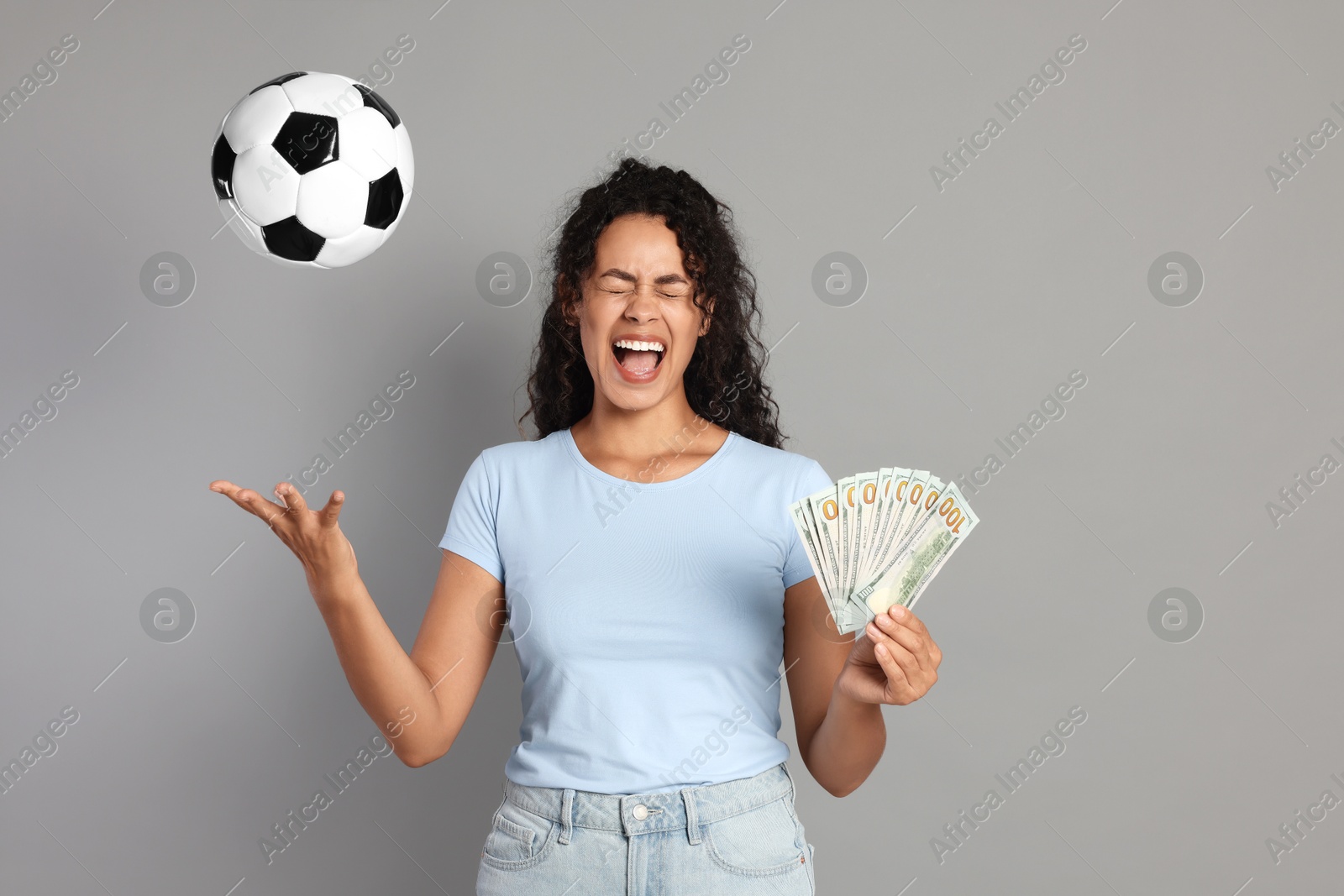 Photo of Happy woman with money throwing soccer ball on grey background