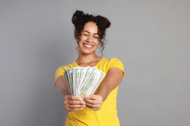 Happy woman with dollar banknotes on grey background