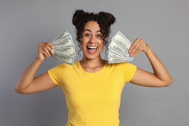 Photo of Happy woman with dollar banknotes on grey background